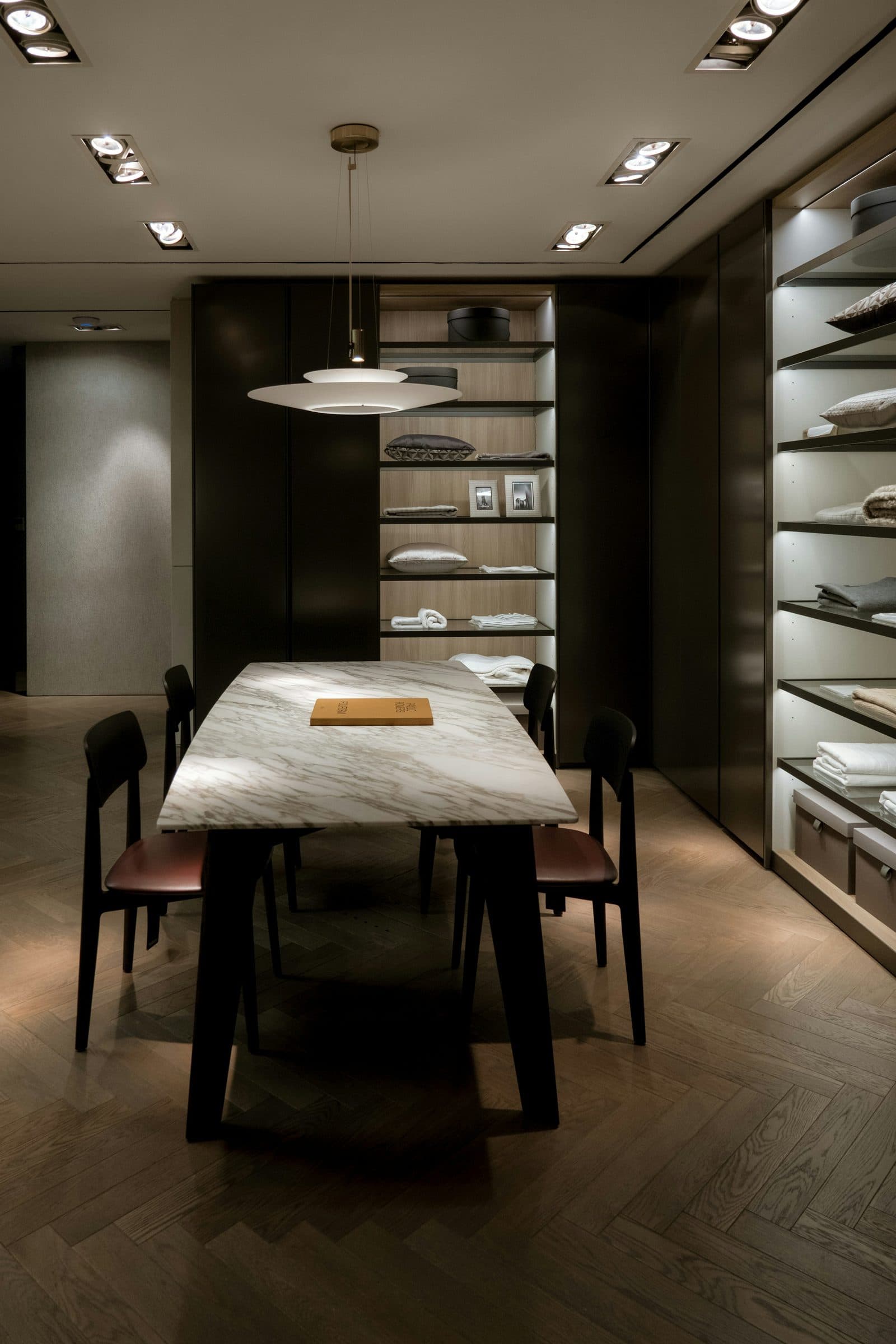 Sala de atendimento privado: mesa de mármore, luz baixa e madeira escura