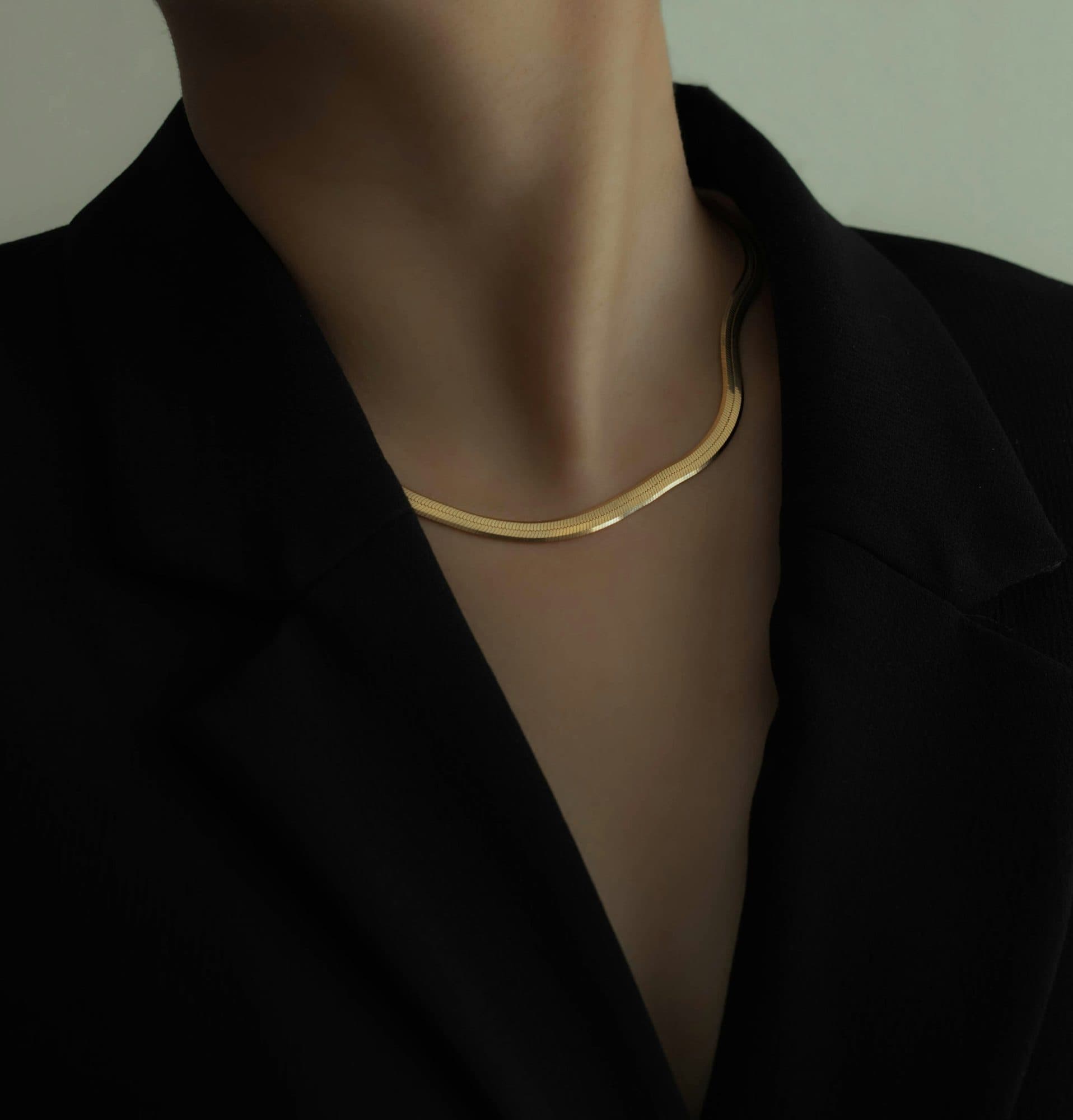 Colar de malha em ouro sobre um blazer preto